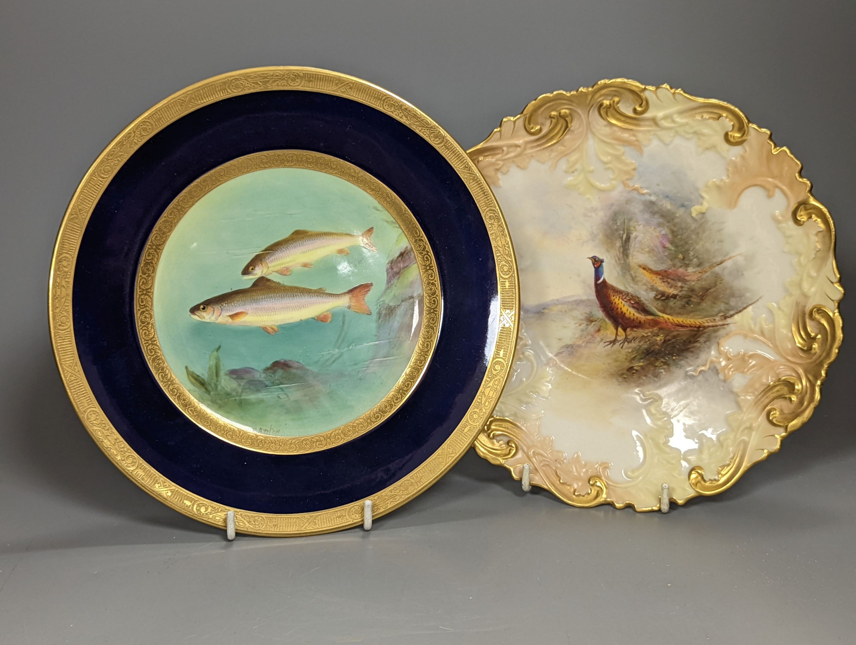 A Royal Worcester moulded plate painted with a brace of pheasants by James Stinton, not signed, date mark 1909 and a Royal Worcester fine plate painted with swimming fish, titled Char, by Harry Aryton, signed date mark f